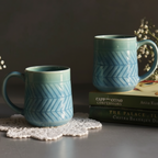 Two blue ceramic mugs on a surface with books and decorative elements.