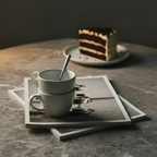 Two white ceramic mugs stacked on a wooden surface with a neutral background