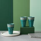 Three blue ceramic cups with a textured finish on a wooden surface.
