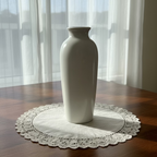 White ceramic vase on a wooden surface with a plain background
