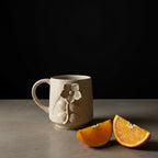 Beige ceramic mug with floral design on a wooden surface